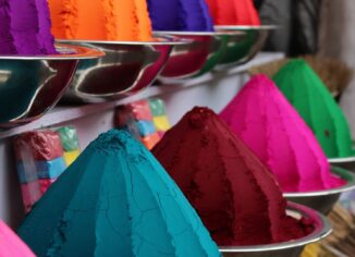 Brightly colored pigment powders displayed in metal bowls and cones
